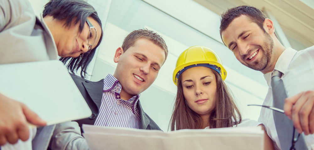 group of people looking at plans girl with yellow hard hat smiling business people