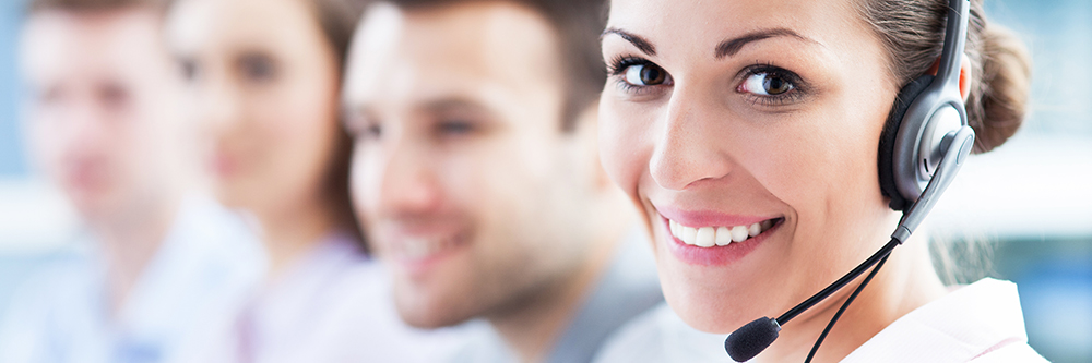 happy woman with call head set on at call center with blurry background people behind her emergency assitance