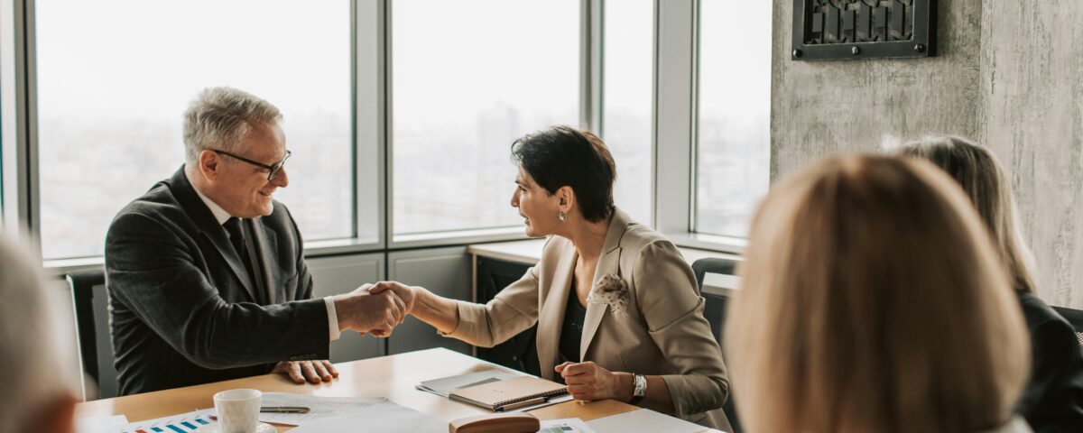 Business professionals shaking hands during a financial meeting, symbolizing trust and transparency in HOA financial management.