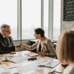 Business professionals shaking hands during a financial meeting, symbolizing trust and transparency in HOA financial management.