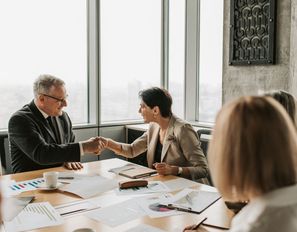 Business professionals shaking hands during a financial meeting, symbolizing trust and transparency in HOA financial management.
