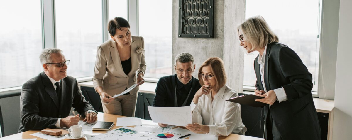 HOA board members and mediators discussing documents during a community dispute resolution meeting.